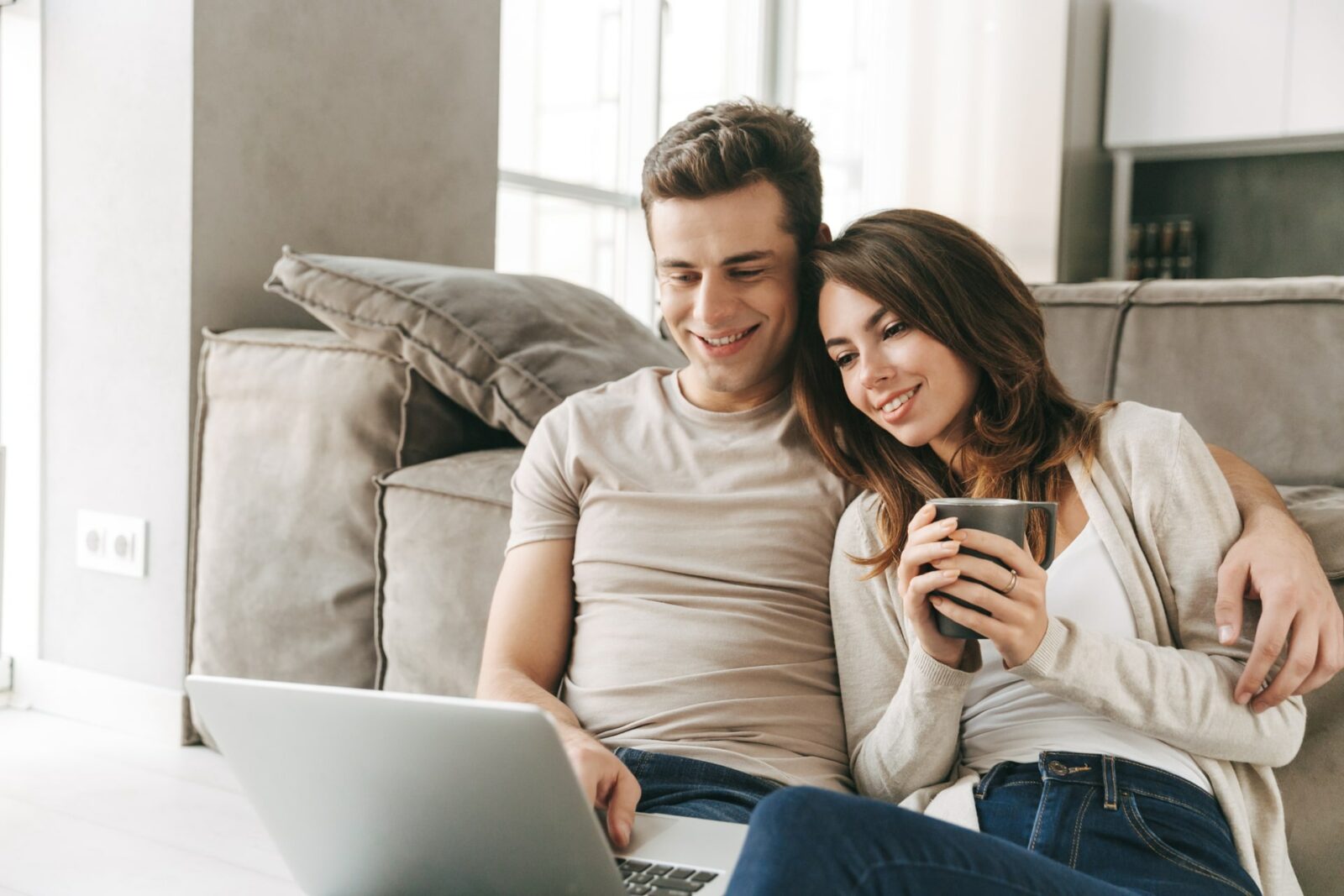 Smiling young couple relaxing on a couch using laptop
